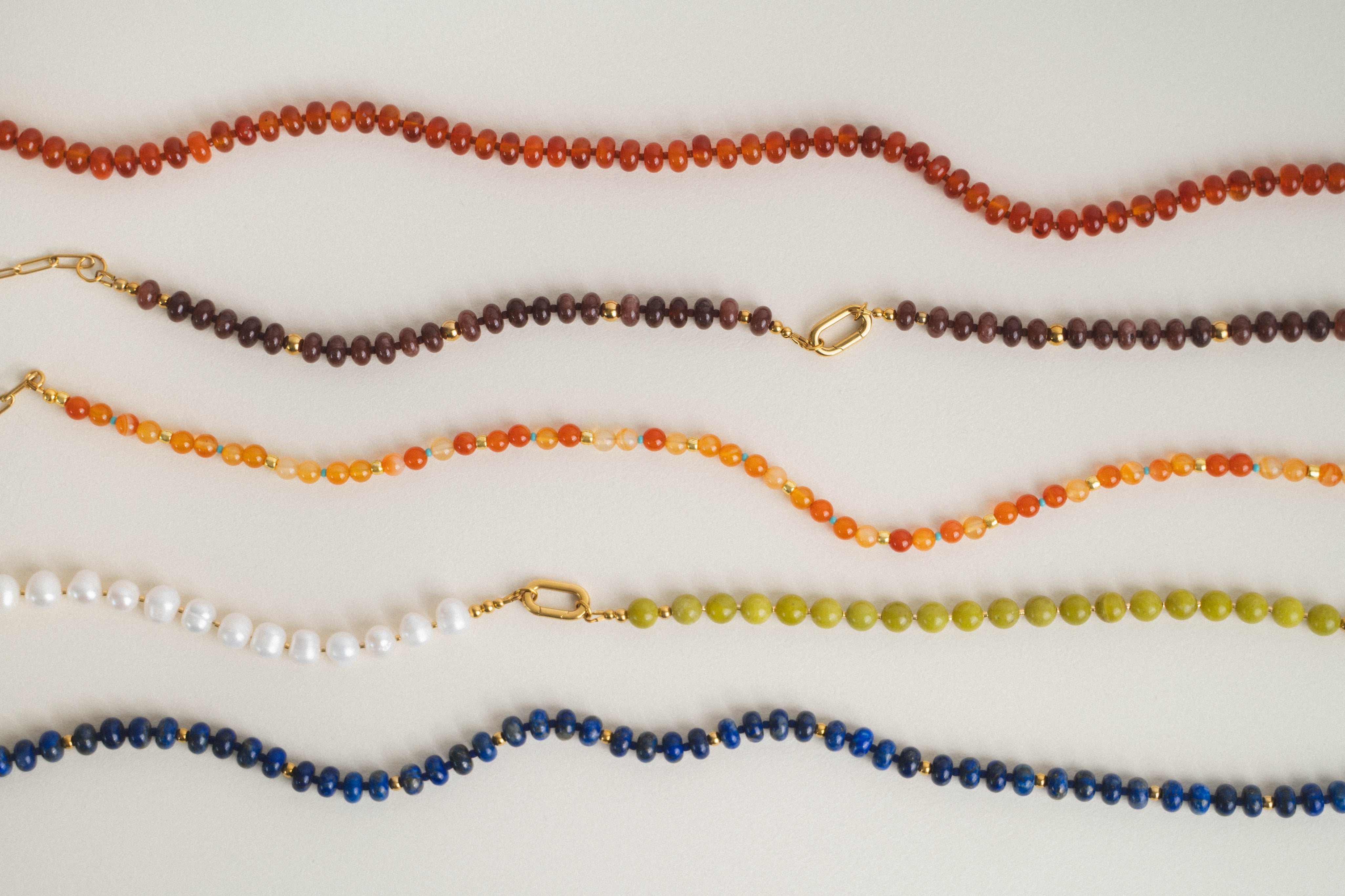 Set of beaded necklaces in various colors on a white background