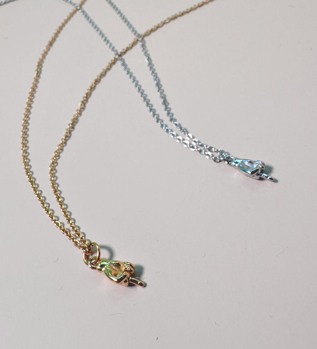 two charm necklaces with middle finger in gold and silver