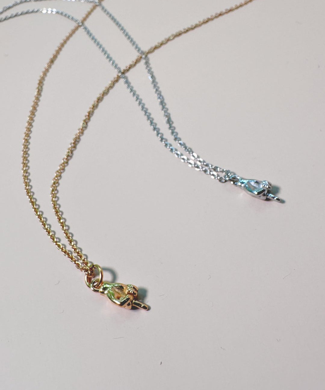 two charm necklaces with middle finger in gold and silver