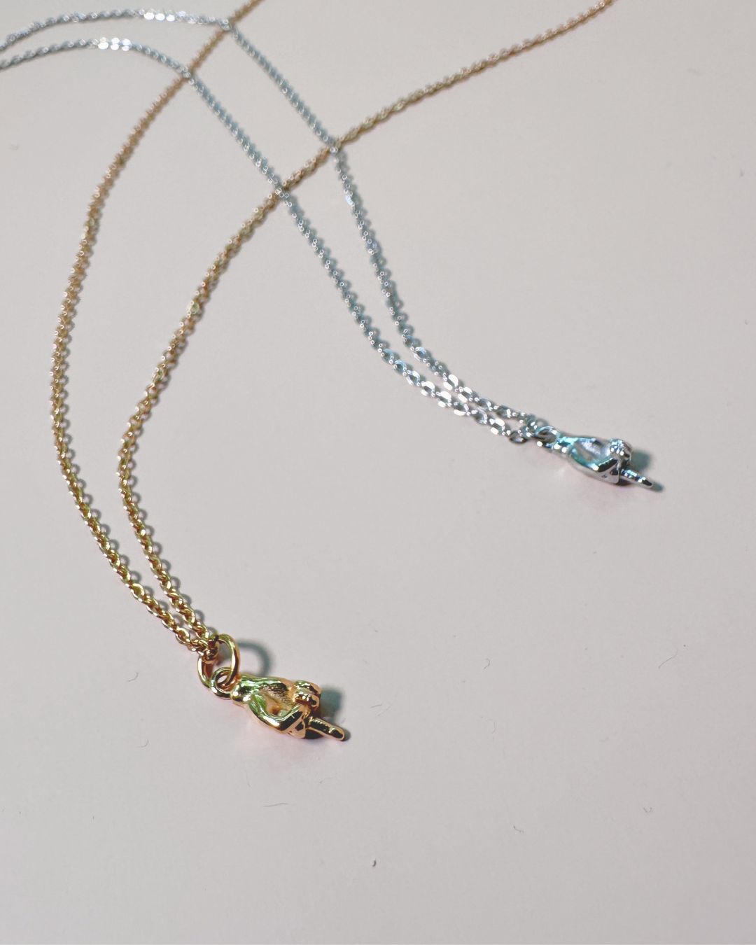 two charm necklaces with middle finger in gold and silver