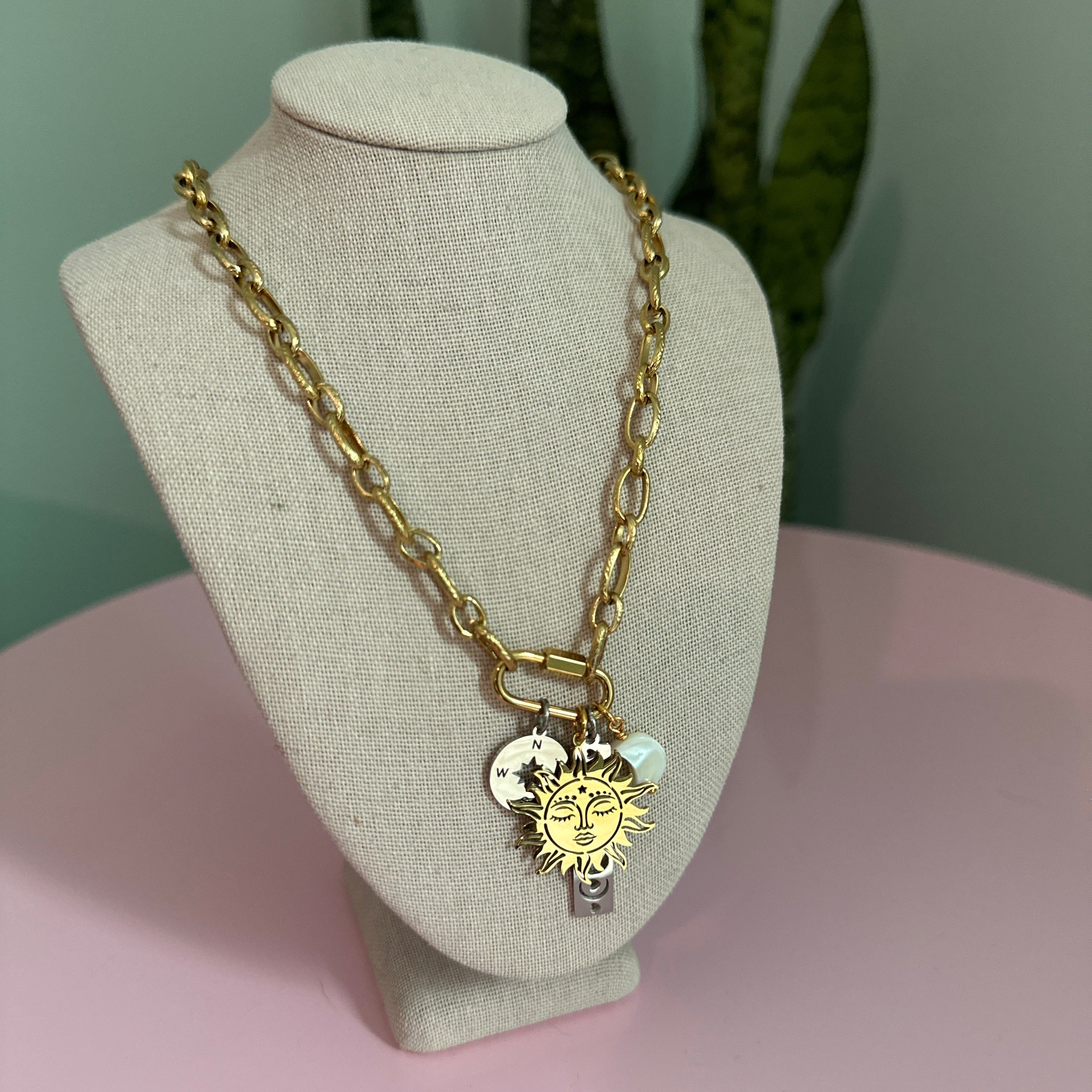 Gold chain bracelet with a lion charm on a mannequin bust against a pink background