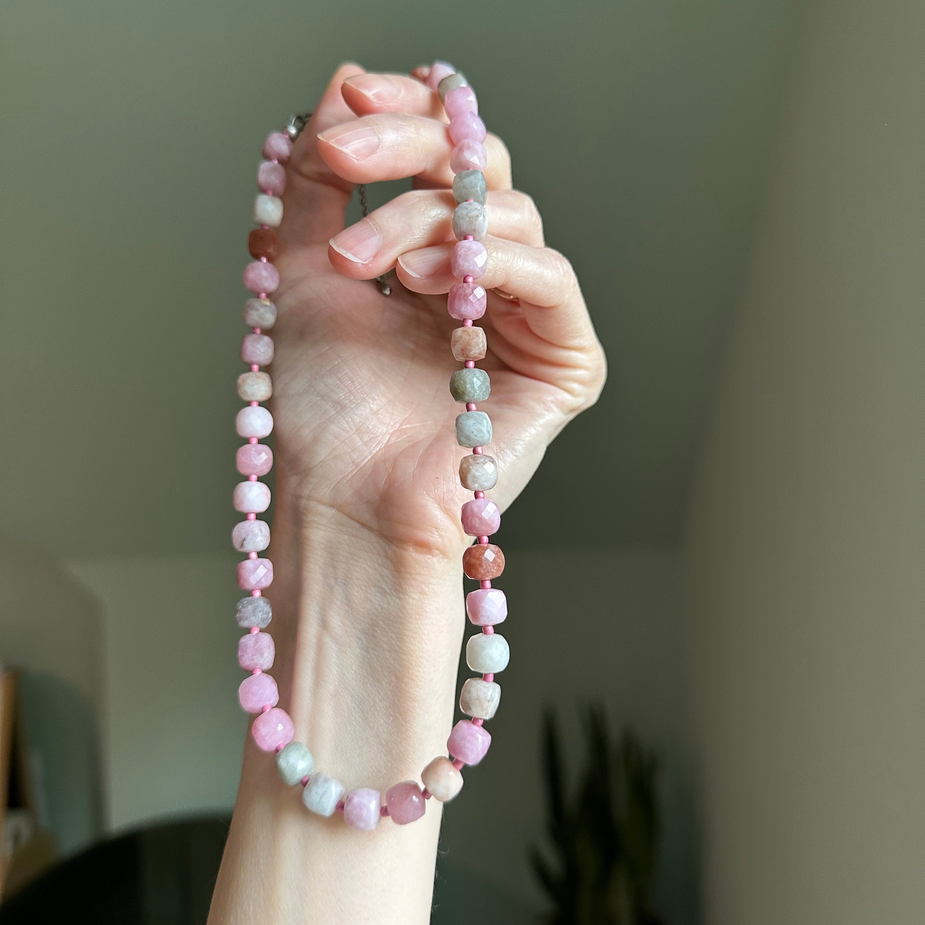 Hand holding a beaded necklace with a blurred background