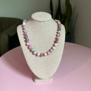 Beaded bracelet on a beige display stand with a pink background