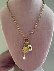 Gold necklace with sun pendant and pearl on a mannequin bust.