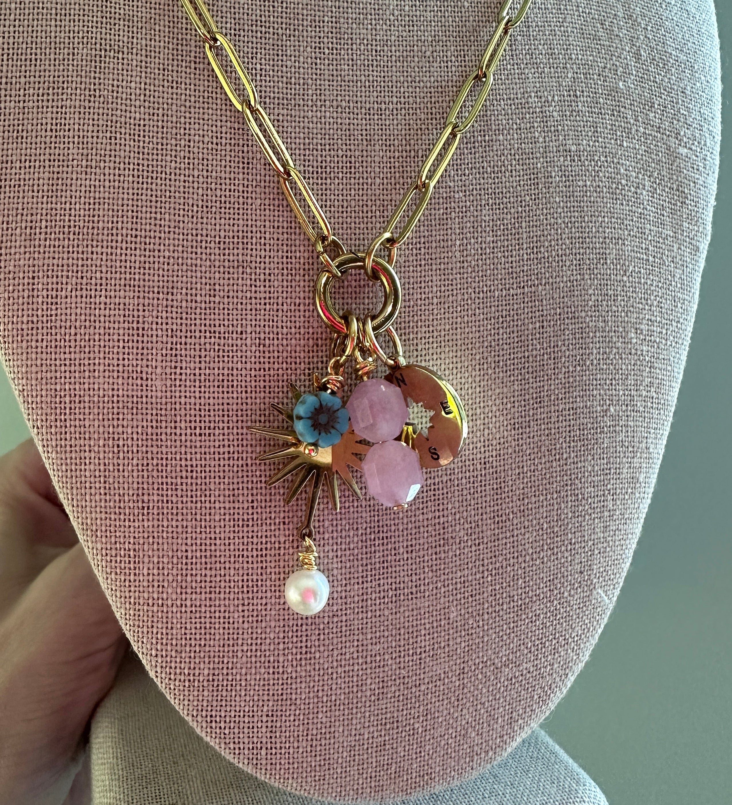 Delicate necklace with floral pendant on a pink jewelry display