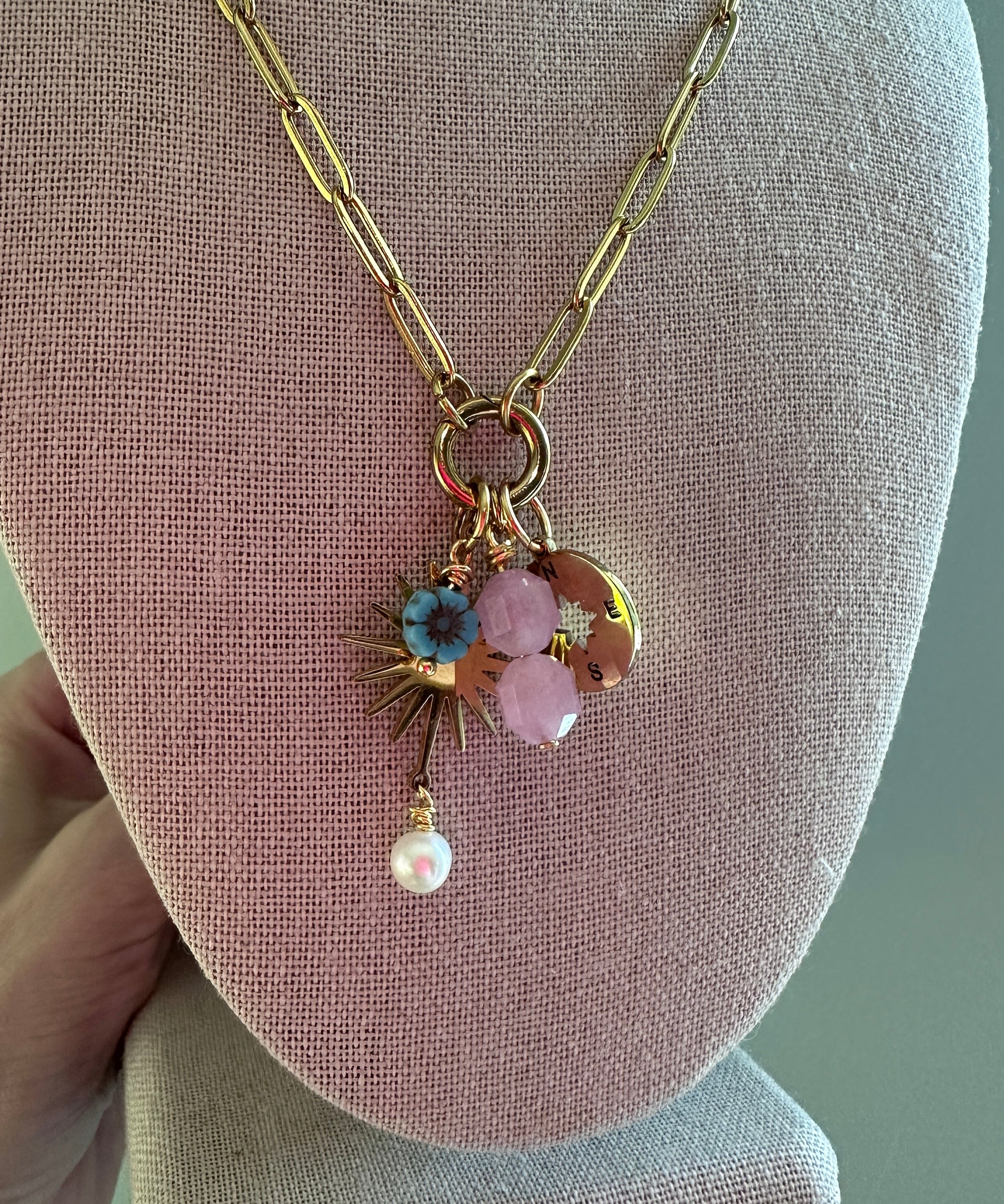 Delicate necklace with floral pendant on a pink jewelry display