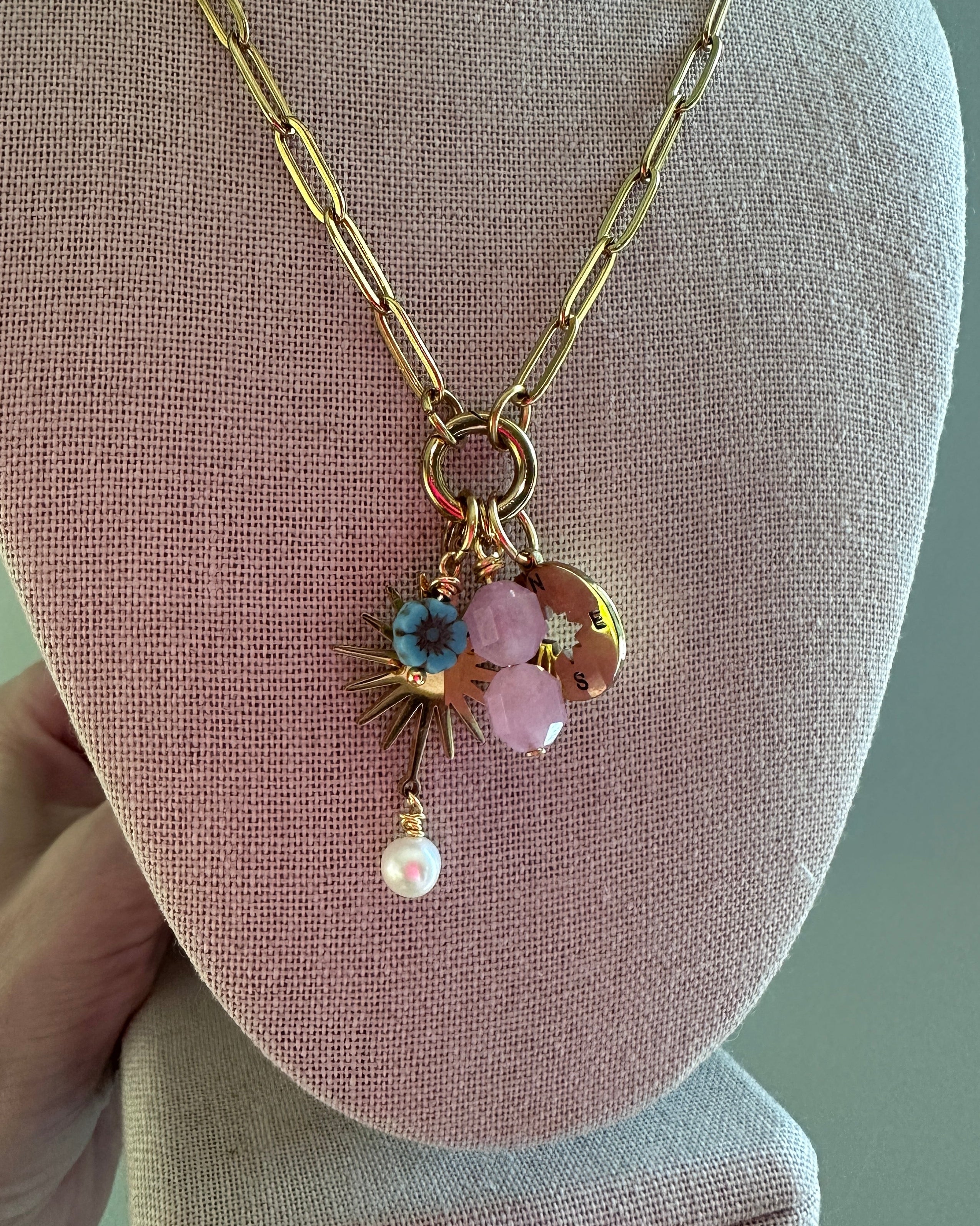 Delicate necklace with floral pendant on a pink jewelry display