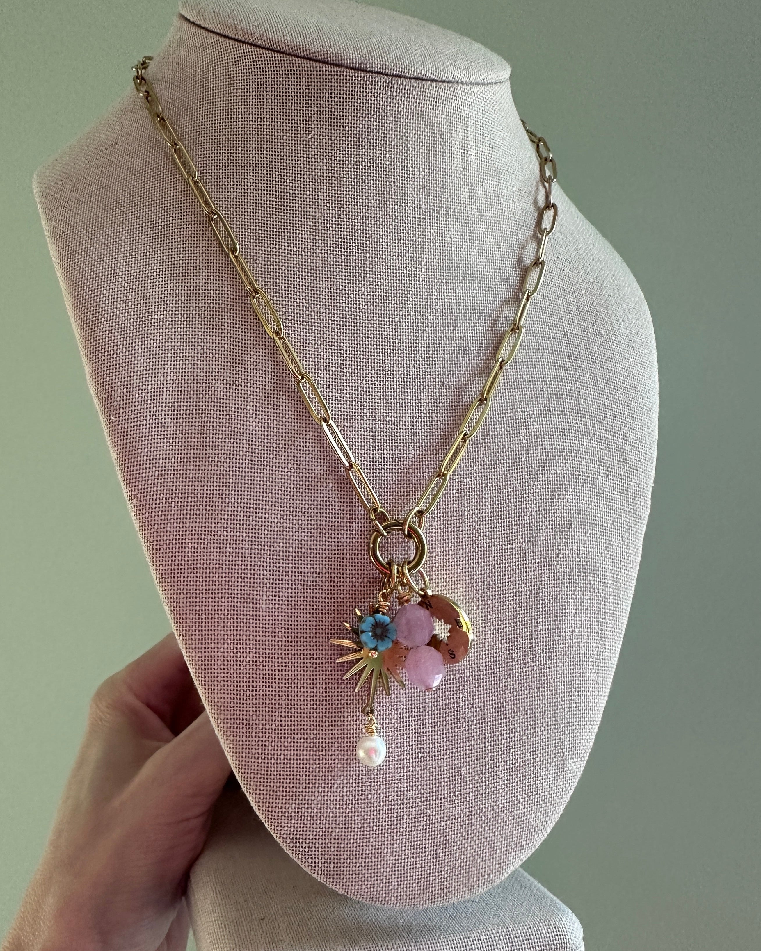 Necklace with charms on a mannequin bust against a plain background