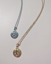 flat lay of two lion charm necklaces in gold and silver