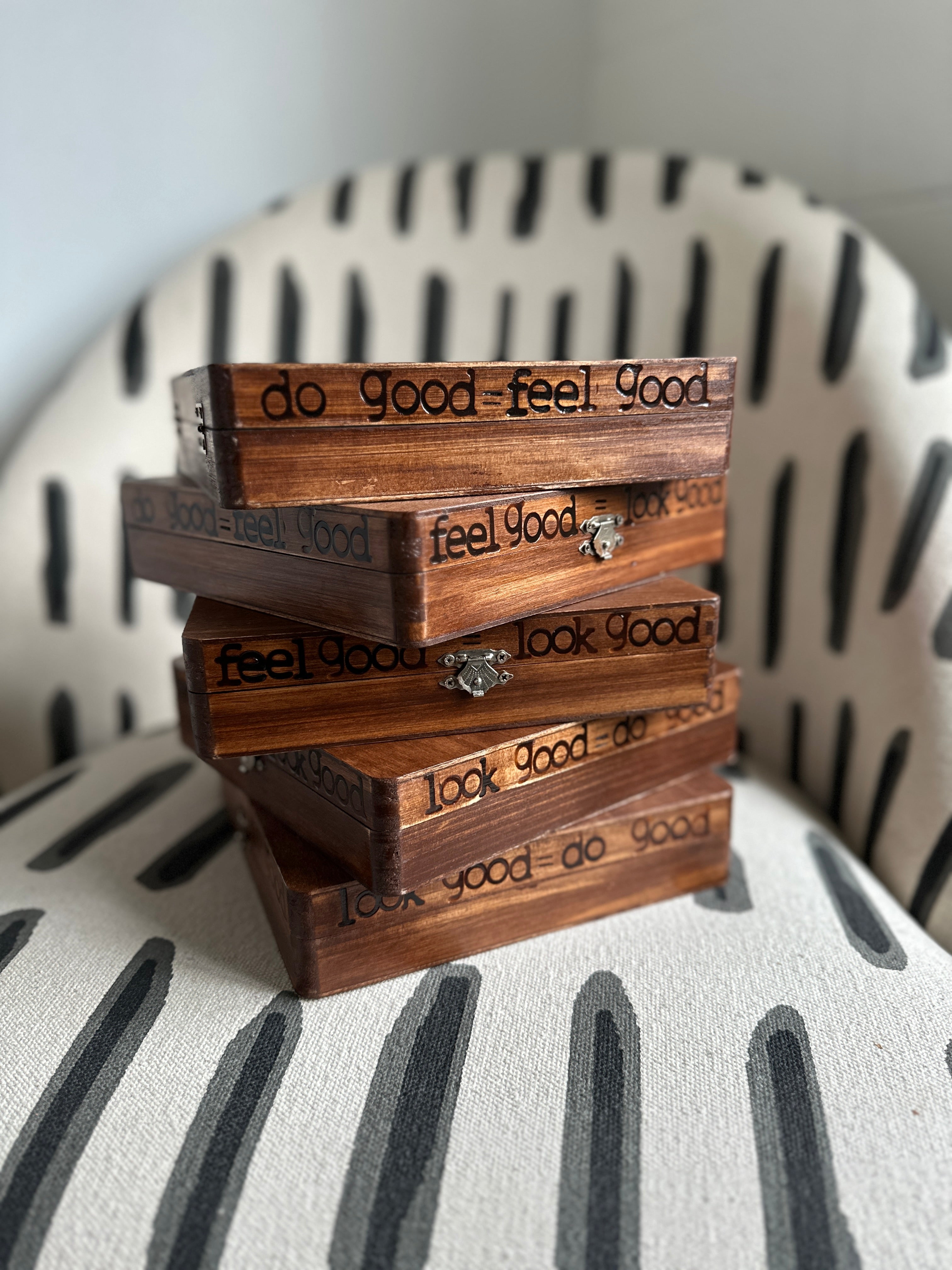 Stack of wooden boxes with 'do good feel good' text on a striped chair.