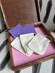White fabric face masks on a pink tray with color swatches, on a patterned surface.
