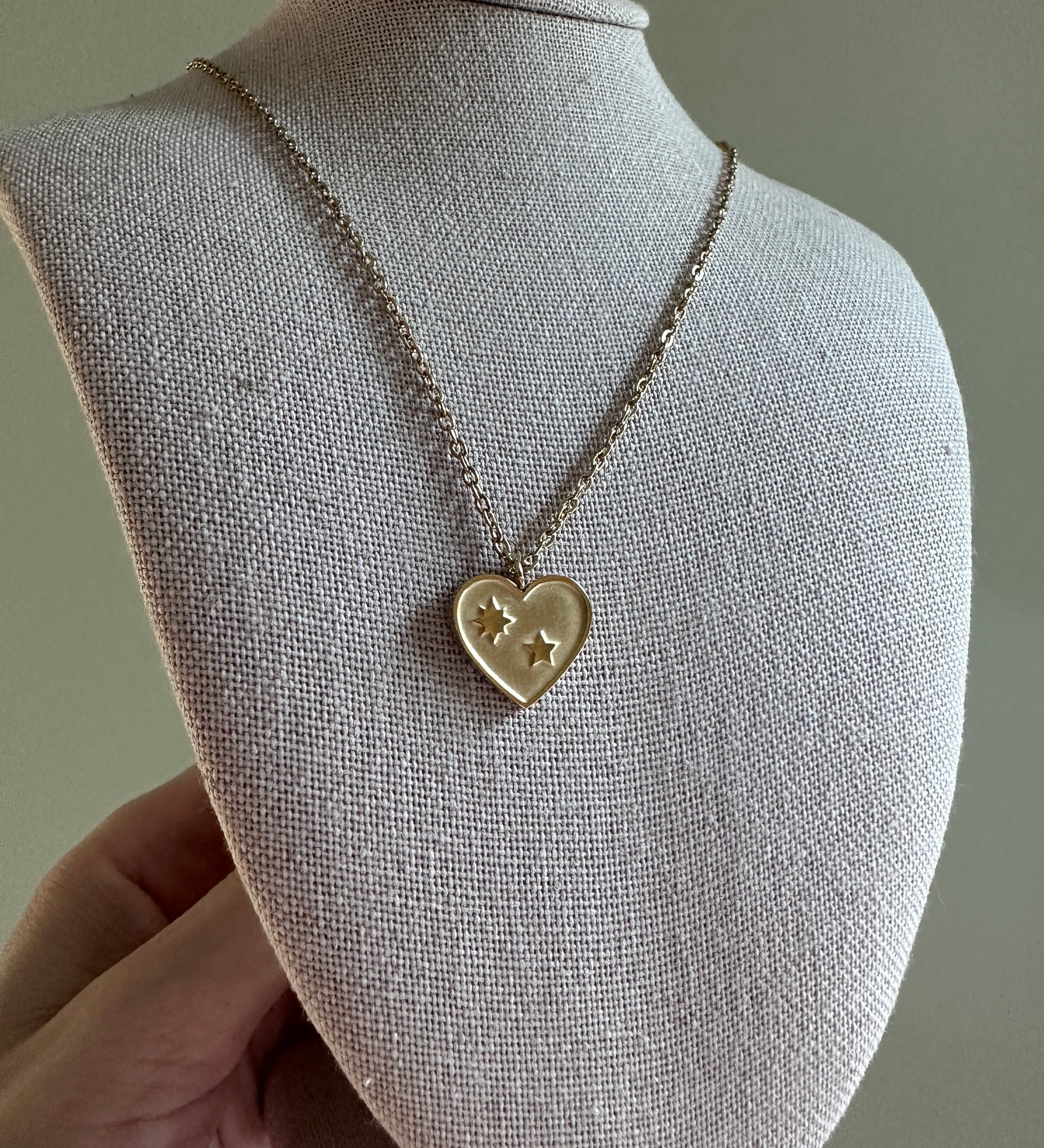 Heart-shaped pendant necklace on a mannequin bust against a neutral background