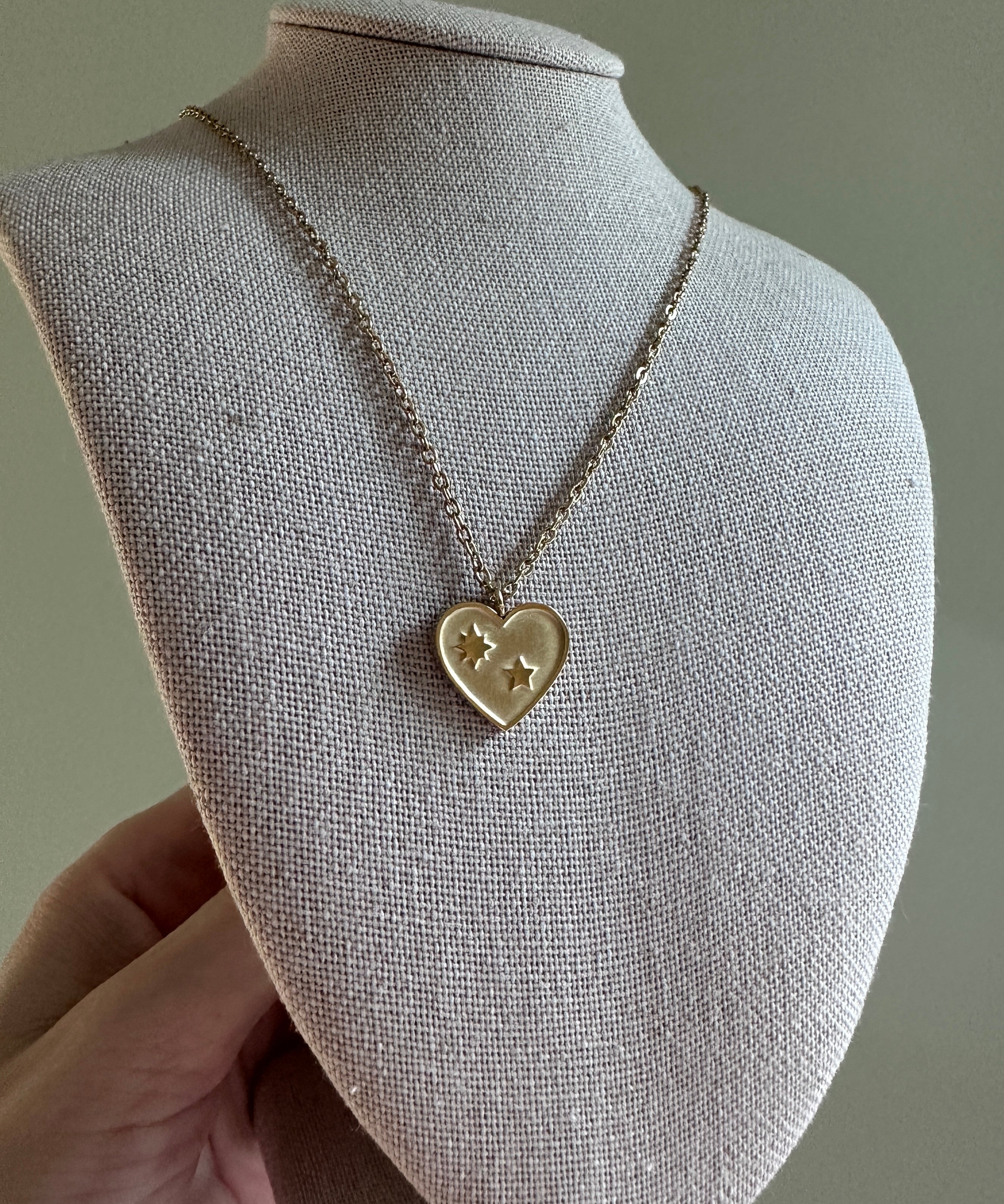 Heart-shaped pendant necklace on a mannequin bust against a neutral background