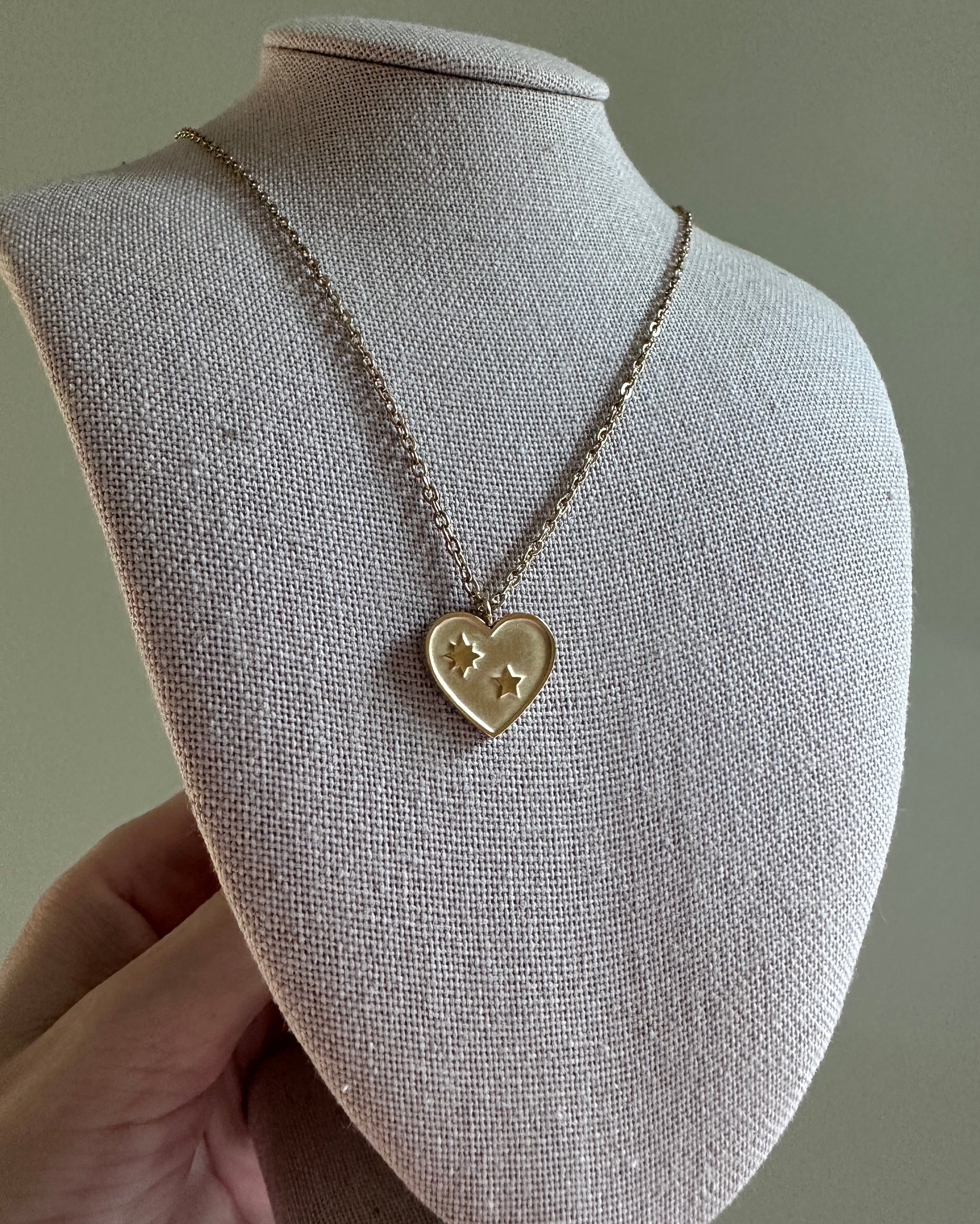 Heart-shaped pendant necklace on a mannequin bust against a neutral background