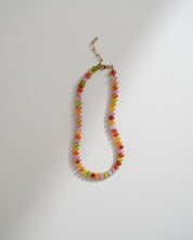 A beaded necklace with small multicolored round beads in orange, yellow, green, and pink, finished with a gold-tone lobster clasp, shown on a plain light background.