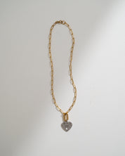 A gold paperclip chain necklace with a small heart-shaped pendant, photographed against a plain white background.