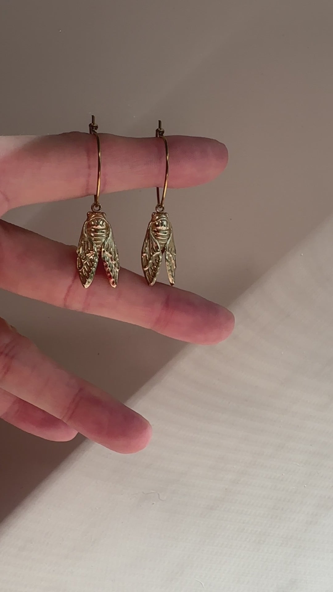 video of cicada earrings hanging from a finger