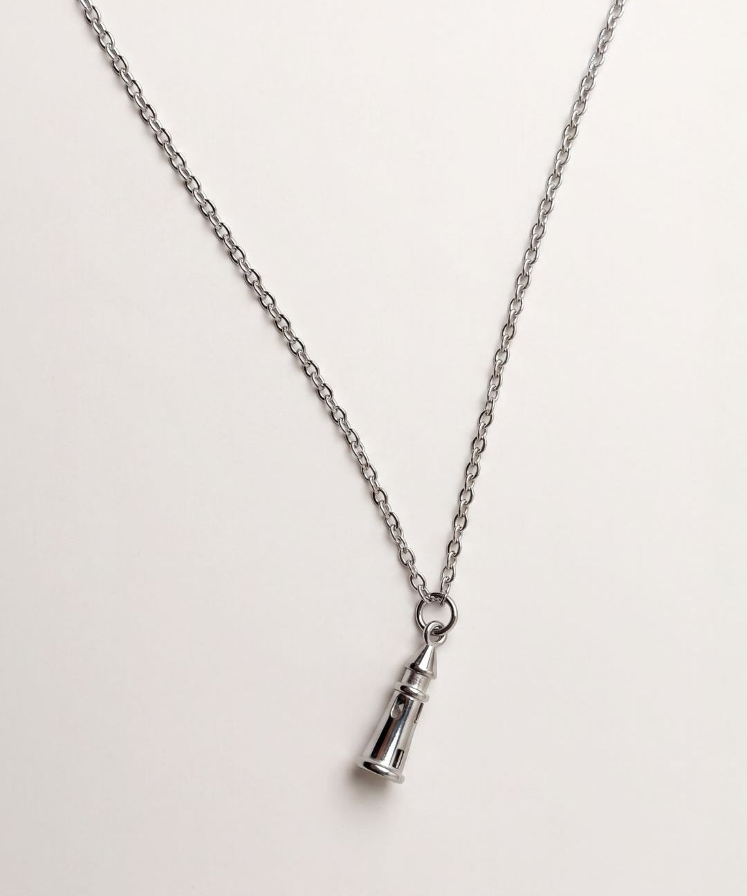 A silver-toned chain necklace with a small lighthouse charm, shown on a plain light background.