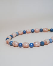 A beaded strand necklace or bracelet made of alternating pink and blue marbled beads, photographed on a plain light background.